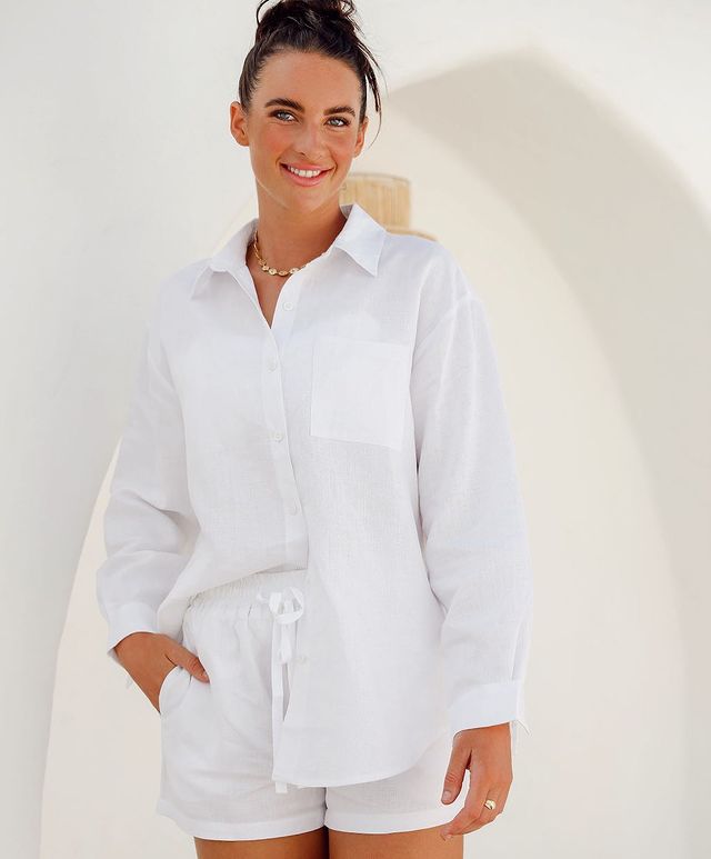Woman wearing white button-down shirt and white shorts